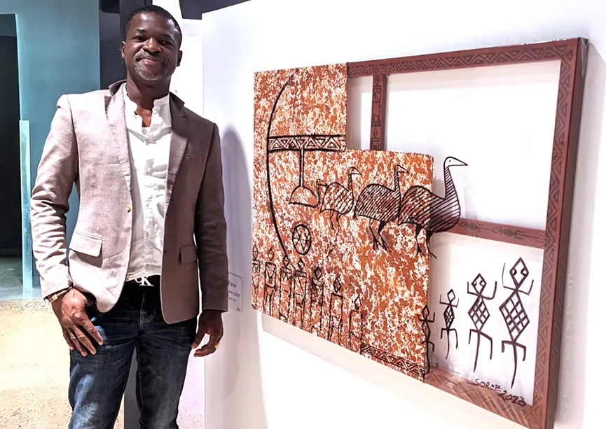 Soro Zana devant l’un de ses tableaux. L’œuvre alliant plusieurs techniques artistiques représente les origines africaines de l’artiste.